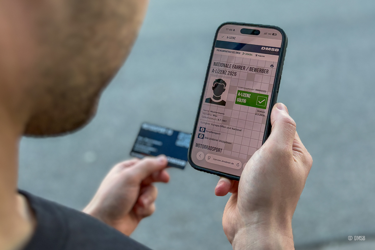 Digitale DMSB-Fahrerlizenz Eine Person hält ein Smartphone in der Hand, auf dem eine digitale gültige DMSB A-Lizenz 2026 zu sehen ist und hat im Hintergrund in der anderen Hand die Motorsport-ID-Checkkarte